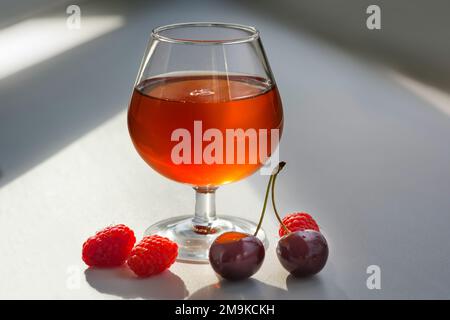 Framboises et cerises fraîches avec un verre de vin Banque D'Images