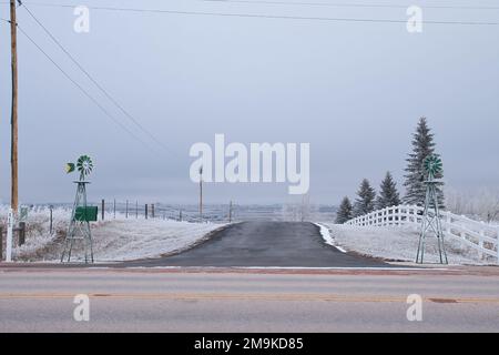 Gillette, Wyoming - 25 janvier 2019: Deux moulins à vent décoratifs à côté d'une route bordée de clôtures et d'arbres près de Sleepy Hollow à Gillette, Wyoming sur un Banque D'Images