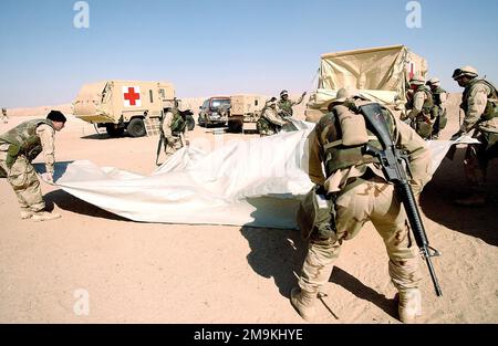 US Navy (USN) Hospital Corpsman second Class (HM2) Daniel Smith (premier plan) et US Marine corps (USMC) Marines affectés au 2nd Bataillon médical, 2nd Force Services support Group (FSSG), déballent un abri de protection biologique chimique (CBPS), à partir de son véhicule à capacité étendue (ECV) de M1113 au Camp Coyote, Koweït, Pendant l'opération, LIBERTÉ DE MOUVEMENT. Le CBPS est un système d'abris hautement mobile et chimiquement protégé conçu pour une utilisation médicale d'urgence dans les zones de combat avant. Objet opération/série: LIBERTÉ DURABLE base: Camp Coyote pays: Koweït (KWT) Banque D'Images