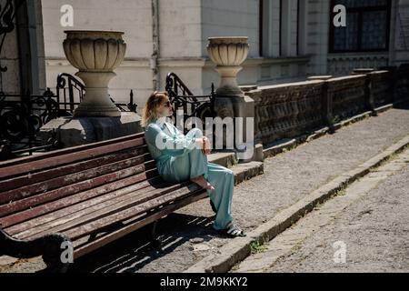 une belle femme mûre en costume bleu est assise sur un banc Banque D'Images