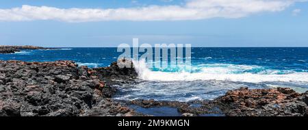 Côte sauvage rocheuse de Fuerteventura, îles Canaries, Espagne. Une grande vague s'écrase sur les rochers de la baie rocheuse. Bannière horizontale. Banque D'Images