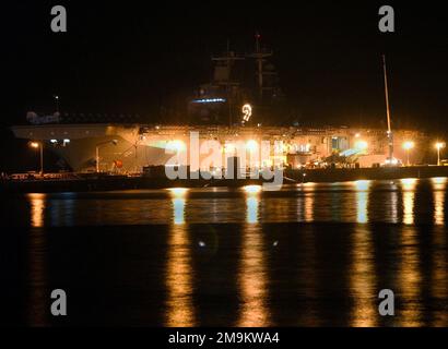 Vue du côté du port de la CLASSE WASP de la marine américaine (USN) : navire d'assaut amphibie, USS ESSEX (LHD 2), amarré à la tarte, tout en effectuant des opérations de chargement de nuit à l'installation portuaire de White Beach, située à Okinawa, au Japon. État: Okinawa pays: Japon (JPN) Banque D'Images