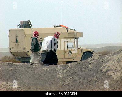 Deux civils iraquiens traversent un Marine corps américain (USMC) 5th Marines, 1st Marine Division (MARDIV), Camp Pendleton, Californie (CA), M997 High-Mobility Multipurpose Roed Vehicle (HMMWV), une partie d'un convoi qui s'est arrêté pour se ravitailler pendant l'opération LIBERTÉ IRAKIENNE. (Image sous-standard). Objet opération/série: LIBERTÉ IRAQUIENNE pays: Irak (IRQ) Banque D'Images