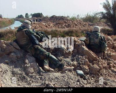 US Marine corps (USMC) Marines de Echo Company (CO), 2nd Bataillon (BN), 5th Marines (MAR) (2/5), équipe de combat régimentaire 5 (RCT-5), 1st Marine Division, Marine corps base (MCB) Camp Pendleton, Californie (CA), s'arrêtent pour un arrêt de sécurité en route vers Bagdad pendant l'opération LIBERTÉ IRAQUIENNE. Une famille iraquienne, en arrière-plan, tente de passer par leur position. (Image sous-standard). Pays: Irak (IRQ) Banque D'Images