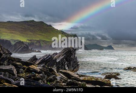 Vue depuis la plage de Clogher Strand, l'océan, les montagnes et le ciel nuageux avec l'arc-en-ciel, la péninsule de Dingle sur la côte atlantique sud-ouest de l'Irlande Banque D'Images