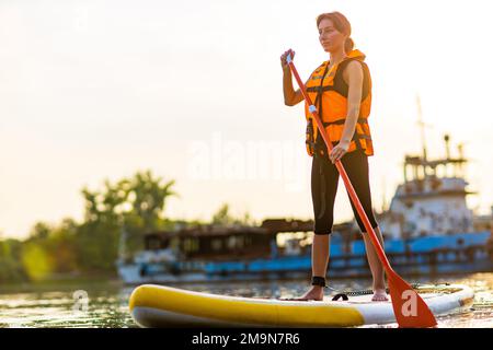 jeune femme en veste de sauvetage orange à bord du souper à la rivière Banque D'Images