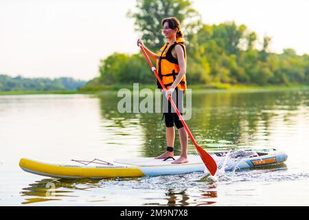 jeune femme en veste de sauvetage orange à bord du souper à la rivière Banque D'Images