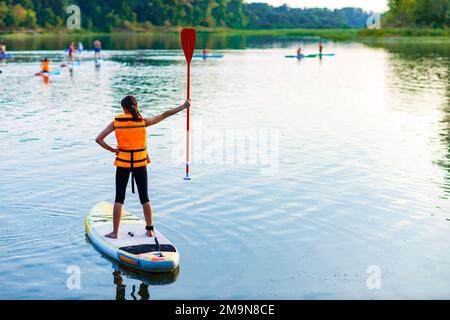 jeune femme en veste de sauvetage orange à bord du souper à la rivière Banque D'Images