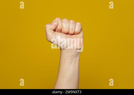 Poing fermé, isolé sur fond orange. Main d'homme forte avec un poing. Alpha. Protestation Banque D'Images