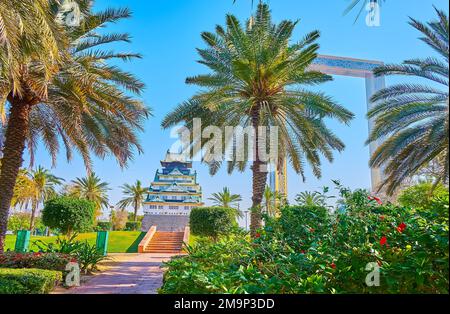 DUBAÏ, Émirats Arabes Unis - 6 MARS 2020 : les palmiers luxuriants et les buissons verts du parc Zabeel avec le cadre de Dubaï et le mini château d'Osaka en arrière-plan, sur 6 mars à Dub Banque D'Images