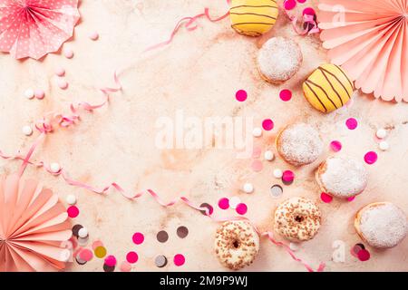 Berliner traditionnel pour le carnaval et la fête. Krapfen allemand ou beignets avec des banderoles et des confettis. Image de carnaval ou d'anniversaire colorée Banque D'Images