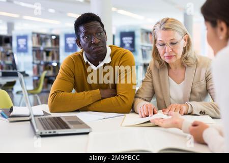 Une femme aide les élèves à se préparer à l'examen en bibliothèque Banque D'Images