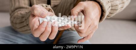 vue partielle de l'homme âgé avec la maladie de parkinson tenant des pilules dans les mains tremblantes, bannière, image de stock Banque D'Images