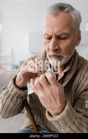 homme âgé souffrant de parkinsonisme et tenant des pilules dans les mains tremblantes, image de stock Banque D'Images