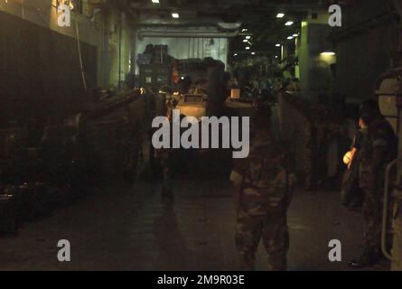 À l'intérieur du pont du puits, à bord du navire d'assaut amphibie USS NASSAU (LAH-4) de la marine américaine (USN), du personnel de l'USN et du corps de la marine américaine (USMC) affecté au peloton de char, à l'équipe d'atterrissage du Bataillon (BLT), 2nd Bataillon, 2nd Marines, 24th Marine Expeditionary Unit (MEU), Special Operations Fable (SOC), Observez qu'un char de combat principal (MBT) USMC M1A1 est chargé sur un engin d'embarcation (LCU), pendant l'opération ENDURING FREEDOM. (Image sous-standard). Objet opération/série : BASE DE LIBERTÉ DURABLE : USS Nassau (LHA 4) Banque D'Images