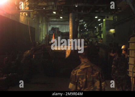 À l'intérieur du pont du puits, à bord du navire d'assaut amphibie USS NASSAU (LAH-4) de la marine américaine (USN), du personnel de l'USN et du corps de la marine américaine (USMC) affecté au peloton de char, à l'équipe d'atterrissage du Bataillon (BLT), 2nd Bataillon, 2nd Marines, 24th Marine Expeditionary Unit (MEU), Special Operations Fable (SOC), Regardez le chargement des chars de combat principaux (MBT) de l'USMC M1A1 sur un engin d'embarcation (LCU), pendant l'opération ENDURING FREEDOM. (Image sous-standard). Objet opération/série : BASE DE LIBERTÉ DURABLE : USS Nassau (LHA 4) Banque D'Images