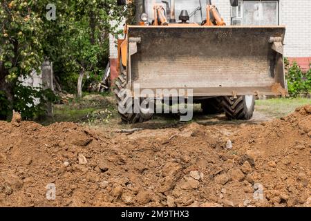 La pelle hydraulique ou le godet de bulldozer aplatit le sol ou la route dans la zone industrielle ou le chantier. Banque D'Images