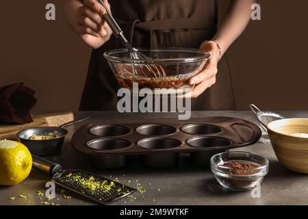 Femme préparant de délicieux muffins dans la cuisine Banque D'Images