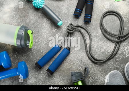 Cordes à sauter avec des équipements de sport, des bouteilles et des baskets sur fond sombre Banque D'Images