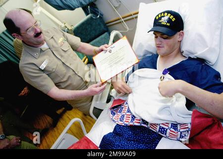 LE contre-amiral (RADM) de la Marine AMÉRICAINE (USN) Michael K. Loose, commandant du Commandement de l'ingénierie des installations navales et CHEF des ingénieurs civils, présente la Médaille du cœur violet à l'USN SEAMAN (SN) Leo 'Jerry' Geibel, opérateur d'équipement Constructionman. SN Geibel, Naval Mobile Construction Battalion Seven four (NMCB-74), Gulfport, Mississippi (MS), a subi de graves blessures aux jambes lorsqu'ils ont dévié une grenade propulsée par des roquettes (RPG) qui explose sur un mur derrière lui dans la région de Ramadi en Irak pendant l'opération LIBERTÉ IRAKIENNE. Les médecins de la Marine de SN Geibel s'attendent à ce qu'il fasse une récupération complète. Base : National Naval Med Banque D'Images
