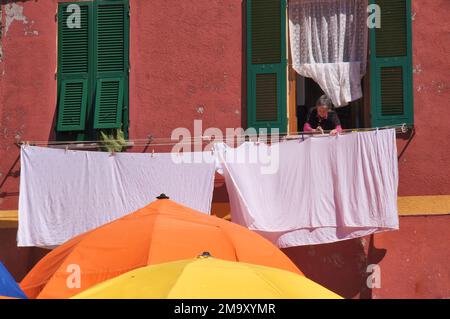 Vernazza: Femme qui se lasse de la fenêtre d'un bâtiment coloré sur la Piazza Guglielmo Marconi à Vernazza, Cinque Terre, la Spezia, Ligurie, Italie Banque D'Images