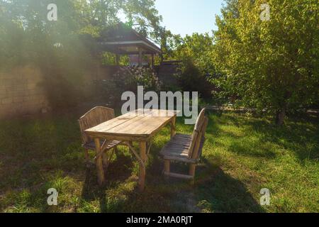Table et bancs en bois faits à la main sur l'herbe dans le jardin de la maison de campagne Banque D'Images