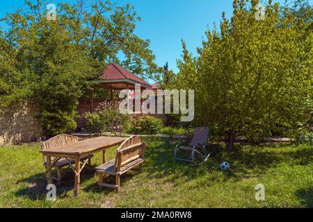 Table et bancs en bois faits à la main sur l'herbe dans le jardin de la maison de campagne Banque D'Images