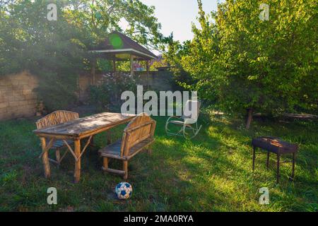 Table et bancs en bois faits à la main sur l'herbe dans le jardin de la maison de campagne Banque D'Images