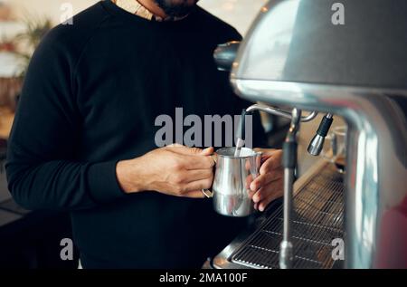 Mains, homme et barista préparant du café au café à l'aide d'une machine pour les boissons chaudes, la caféine ou la vapeur. Main de l'employé, homme, faisant cuire du lait dans un pot métallique pendant Banque D'Images