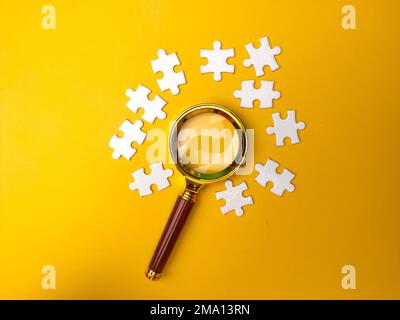 Loupe recherchant le puzzle manquant sur fond jaune Banque D'Images