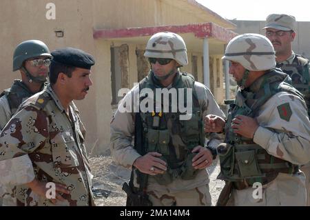 040606-M-5555L-070. [Complet] Légende de la scène : Armée AMÉRICAINE (USA) le lieutenant-colonel (LTC) Richard M. Cabrey, commandant (CO), quartier général et quartier général de la Compagnie (H&HC), 1st Bataillon, 5th Artillerie de campagne, 1st Division d'infanterie, s'entretient avec le major (MAJ) Akarm, S-3 affecté à la Brigade 501st, dans le cadre du rapport après l'action, Après le raid de la maison de pratique, mené près de Camp Hurricane point, situé à la périphérie d'AR Ramadi, en Irak. LES soldats DE l'armée AMÉRICAINE (USA) attachés à la division marine 1st (MARDIV) du corps des Marines des États-Unis (USMC) sont engagés à Traini Banque D'Images
