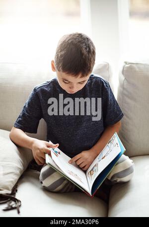 Passe-temps, garçon et lecture sur le canapé, détendez-vous et heureux le week-end, pause et apprentissage. Enfant, enfant et livre pour le plaisir, l'éducation et l'histoire sur le canapé Banque D'Images