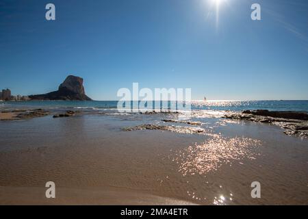 Vue panoramique sur la plage de la petite ville de Calpe sur la Costa Blanca espagnole avec le rocher d'Ifach en arrière-plan sous un grand soleil. Banque D'Images
