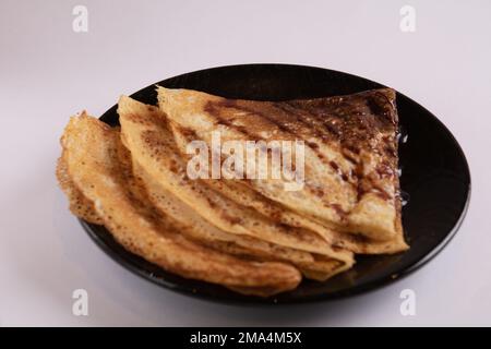 crêpes photo empilées dans des triangles sur une assiette avec du sirop sur un fond clair Banque D'Images