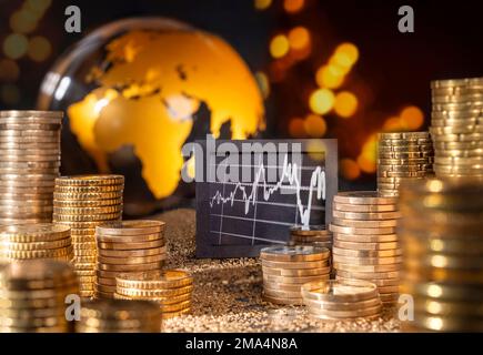 Bourse et économie internationale. Graphique et pile avec de l'argent devant le globe doré. Banque D'Images