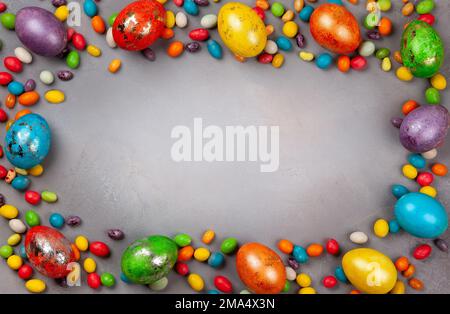 Œufs de Pâques colorés et chocolats bonbons de Pâques sur fond gris. Vue de dessus avec espace de copie. Concept Pâques festive. Banque D'Images