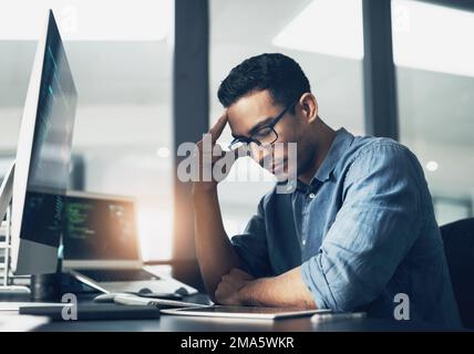 Voir les larmes tomber, laisser être, se déplacer, rien à voir. Un jeune homme regardant stressé en utilisant un ordinateur dans un bureau moderne. Banque D'Images