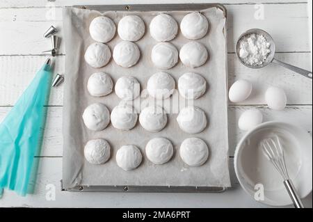 Biscuits au gingembre avec glaçage royal ou glaçage blanc d'œuf sur un plateau de cuisson sur fond blanc d'en haut Banque D'Images
