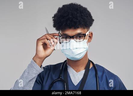 Permettez-moi de vous jeter un œil. un infirmier portant un masque chirurgical debout sur un fond gris. Banque D'Images