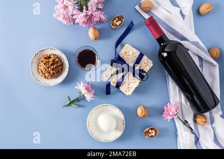 Magnifique fond bleu de la Pâque juive. vue de dessus d'une bouteille de vin casher rouge, verres de vin, matzah, noix, œuf sur une assiette Banque D'Images