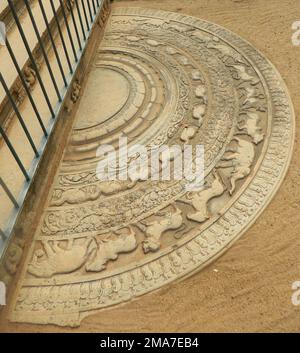 Sandakada pahana, également connu sous le nom de Moonstone, est une caractéristique unique de l'architecture cinghalaise de l'ancien Sri Lanka. C'est une dalle de pierre semi-circulaire sculptée, habituellement placée au fond des escaliers et des entrées. Vu pour la première fois dans la dernière étape de la période Anuradhapura, le pahana de sandakada a évolué à travers les périodes Polonnaruwa, Gampola et Kandy. Selon les historiens, le sandakada pahana symbolise le cycle de Sansāra dans le bouddhisme. L'ancienne chronique de Mahavamsa et de la littérature de Pali comme le Samantapasaadika se réfèrent à la sandakada pahana comme patika. Sri Lanka. La première sandakada pa Banque D'Images