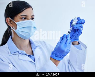 Préparation de votre vaccin. une jeune scientifique attirante utilisant une seringue pour extraire le vaccin covid 19 d'une bouteille dans son laboratoire. Banque D'Images