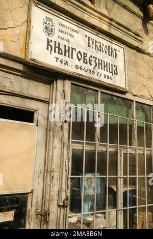 Façade ancienne à Belgrade qui a l'air abandonnée ou déshabituée avec un portrait de Jésus à l'intérieur de la fenêtre qui est barrée et cadenassée. Banque D'Images