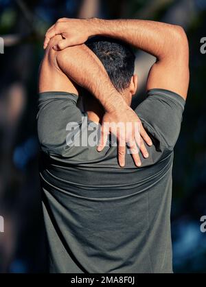 L'étirement permet de garder les muscles souples. Vue arrière d'un jeune homme sportif qui étire les bras tout en s'exerçant à l'extérieur. Banque D'Images