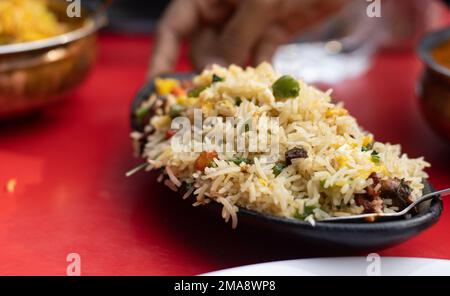 Une assiette de riz frit mélangé - une cuisine indienne chinoise servie sur une table rouge Banque D'Images