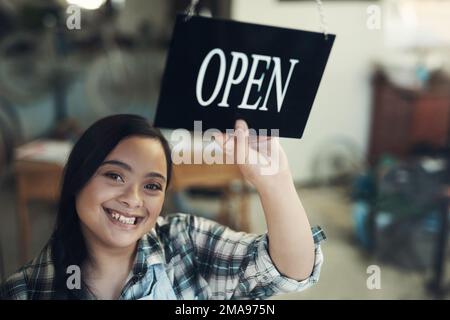 Un autre jour, une autre vie. Portrait d'une jeune femme tournant un panneau ouvert au travail. Banque D'Images