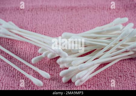 Sélection de tampons de coton Q-Tips avec bâtonnets en carton respectueux de l'environnement pour l'élimination du maquillage sur un fond de tissu éponge rose Banque D'Images