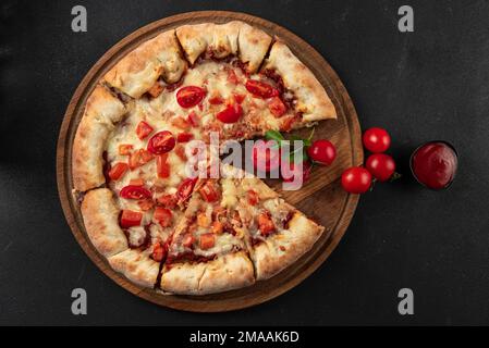 Pizza cuite avec ingrédients à côté de faire sauce tomate, mozzarella, tomates, huile d'olive, fromage, épices, servies sur une table rustique en bois. Forme plate Banque D'Images