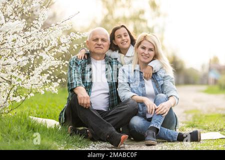 Trois générations de famille assis à l'extérieur dans la nature de printemps Banque D'Images