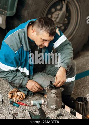 Le mécanicien d'automobiles répare le chariot. Réparation et diagnostic professionnels des tracteurs et équipements cargo. Le mécanicien en atelier considère les pièces de rechange. Banque D'Images